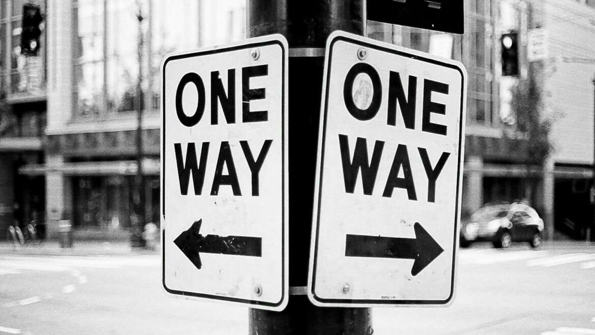 a one way sign on a pole on a city street